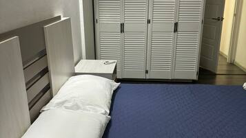 A bedroom with a bed, a nightstand, and a wardrobe.