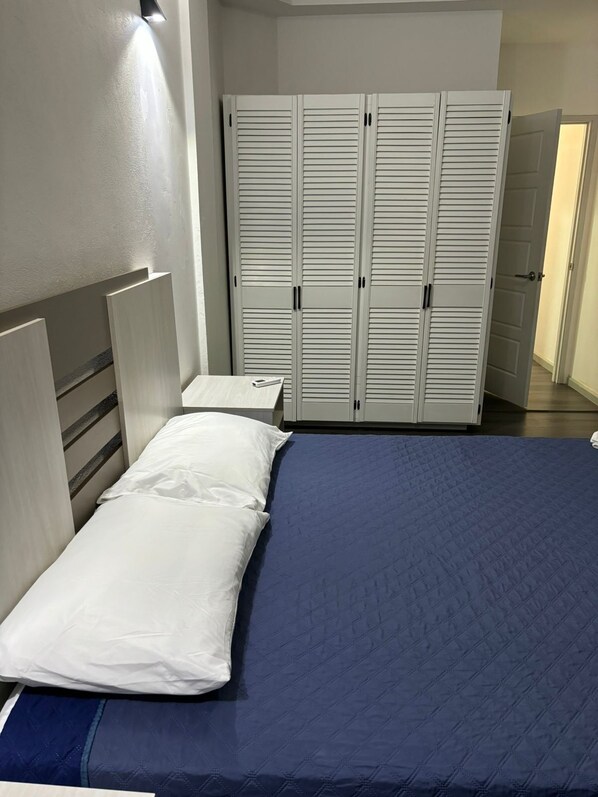 A bedroom with a bed, a nightstand, and a wardrobe.