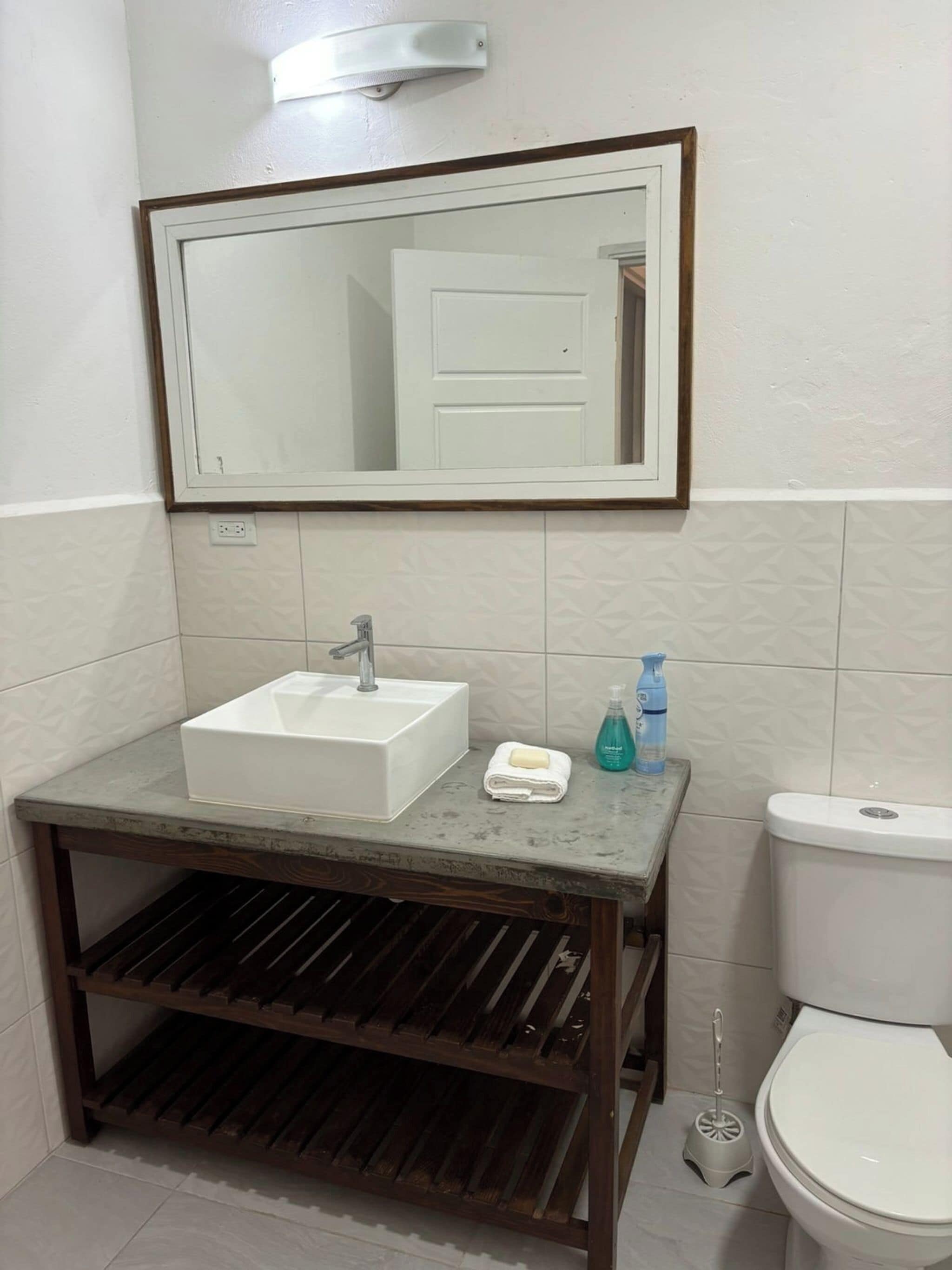 A bathroom with a white sink, mirror, and toilet.