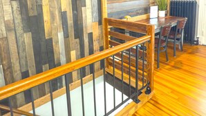 Una escalera de madera con barandilla, un área de comedor con mesa y sillas, y un radiador en la pared.