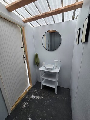Un bagno compatto con un mobile lavabo bianco, uno specchio rotondo e un lavandino piccolo.