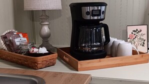 A kitchen counter with a coffee maker, a lamp, and a tray with coffee pods.