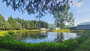 A serene lakeside setting with a pond, lush greenery, and a small building.