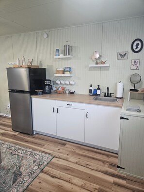 Ett modernt kök med vita skåp, ett kylskåp i rostfritt stål och en bänkskiva i trä.