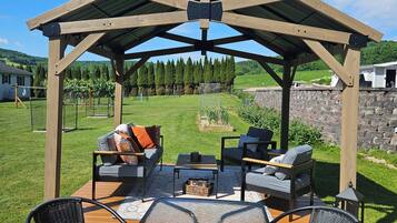 A wooden pergola with a fire pit and seating area.