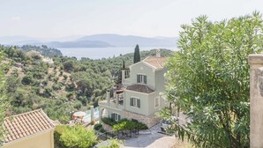 Une villa de style méditerranéen dotée d’un balcon offrant une vue imprenable sur un lac pittoresque et les montagnes.