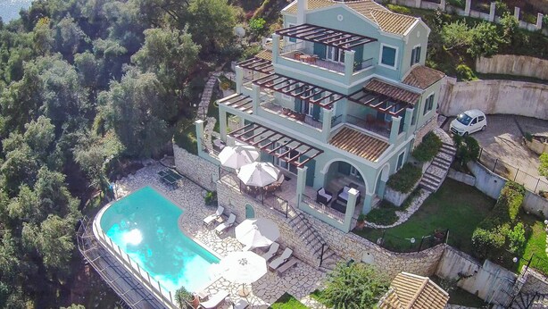 Une maison à plusieurs étages dotée d’une piscine, d’un espace de détente extérieur et offrant une vue sur la forêt environnante.
