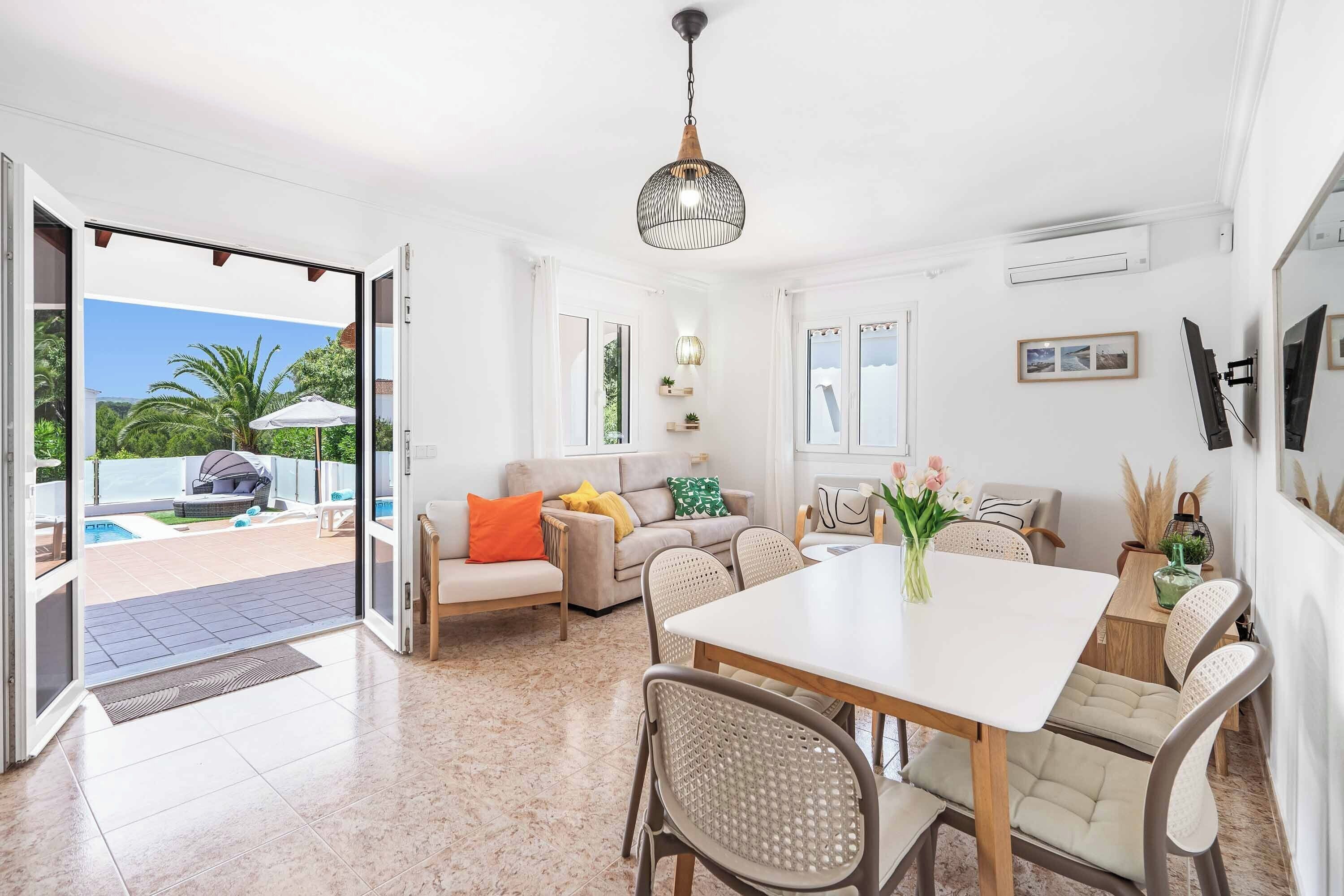 Amplia sala de estar con mesa de comedor, asientos cómodos y vista a una piscina y jardín.
