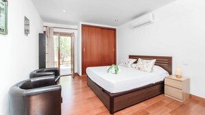Une chambre à coucher avec un lit en bois, une table de chevet avec une lampe, une chaise et une porte donnant sur un balcon.