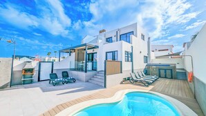 A modern villa with a swimming pool, outdoor seating, and a staircase leading to the upper floor. - Villa Julaga (La Oliva)