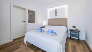 A hotel room with a bed, a bedside table with a lamp, and a small plant. - Villa Julaga (La Oliva)