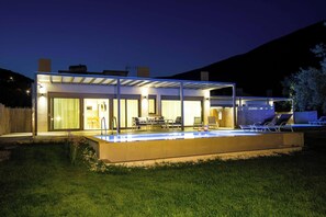A modern house with a swimming pool, outdoor seating, and a covered patio area.