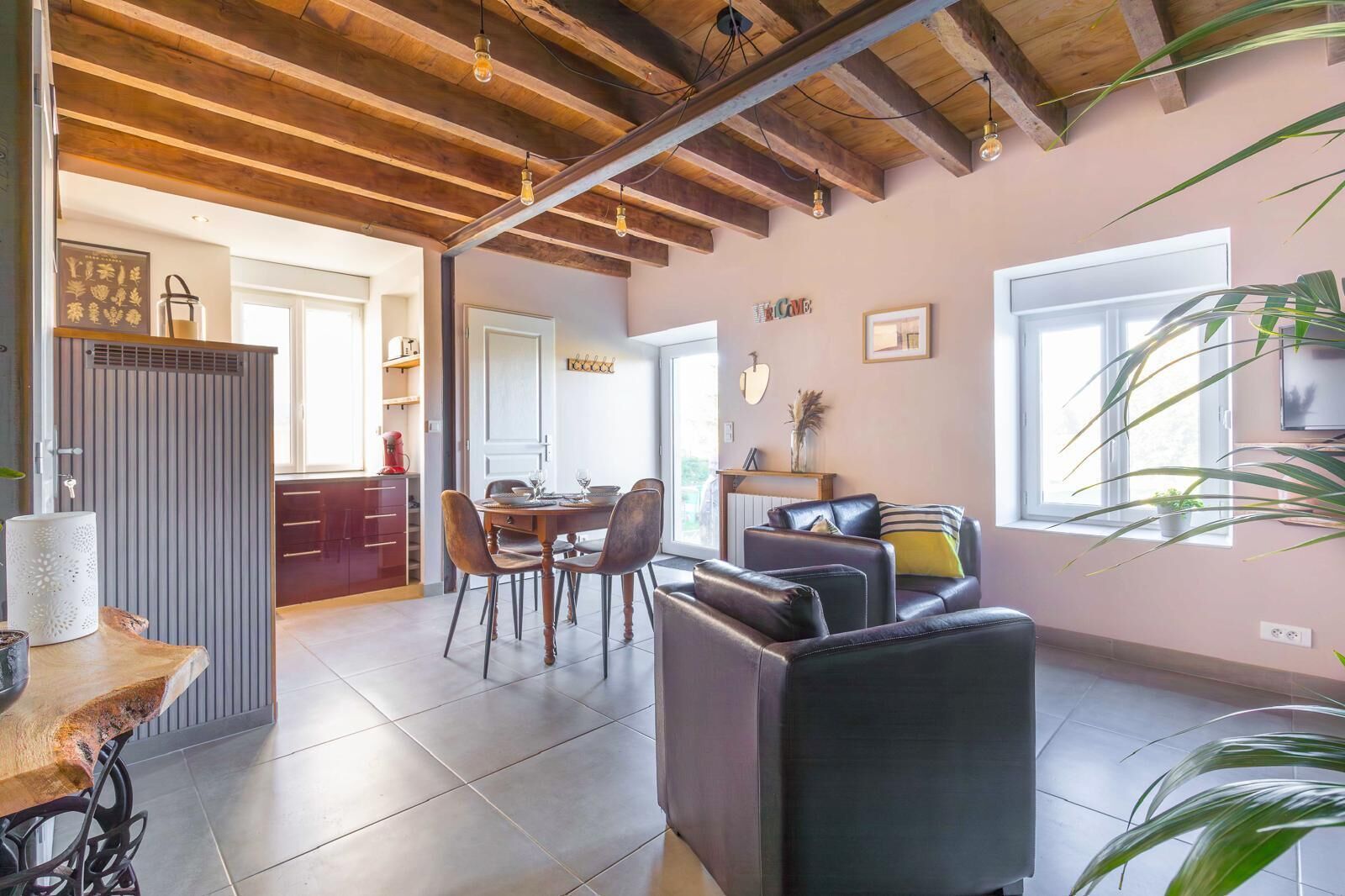 Een ruime woonkamer met een eettafel, leren banken en een keuken met een modern design.