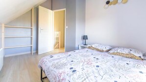 Ein Schlafzimmer mit einem Bett, einem Nachttisch, einer Lampe, einer Wanddekoration und einem eingebauten Bücherregal.