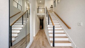 A modern staircase with glass railings and wooden steps, leading to a second floor. - Downtown Dallas Home  (Dallas)