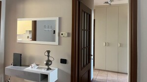 A modern bathroom with a mirror, a vanity, and a door leading to a bedroom.