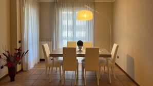 A dining area with a table and chairs, a vase with flowers, and a lamp.