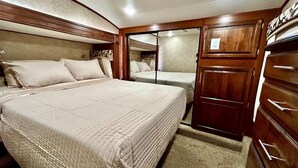 A bedroom with a large bed, wooden cabinets, and a small bathroom.