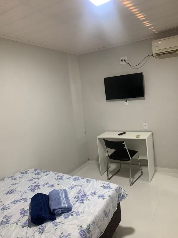 A bedroom with a bed, a desk, and a chair.