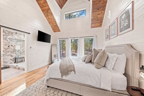 Une chambre avec un grand lit, une télévision et une vue sur l’extérieur.