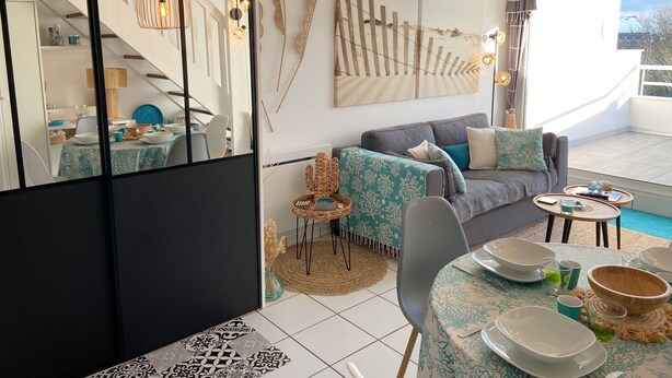 A modern living room with a sofa, dining table, and a staircase.