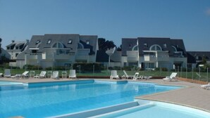A swimming pool with lounge chairs and a modern building in the background.