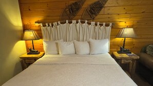 Una cama con ropa de cama blanca, dos mesitas de noche con lámparas y un cabecero de madera.