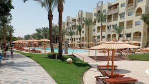 Un resort con piscina, palmeras y zonas de estar al aire libre.