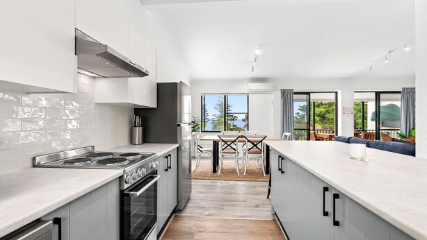 Een moderne keuken met een centraal eiland, een eetgedeelte met uitzicht, en een zithoek met uitzicht.