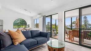 Een moderne woonkamer met een bank, een glazen salontafel en een eethoek met een tafel en stoelen.
