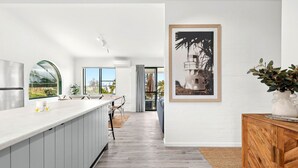 Een moderne keuken met een groot eiland, een eetgedeelte met uitzicht en een lijstwerkkunstwerk aan de muur.