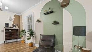 Une pièce avec un fauteuil en cuir, une table en verre, une lampe et des étagères ornées de plantes.