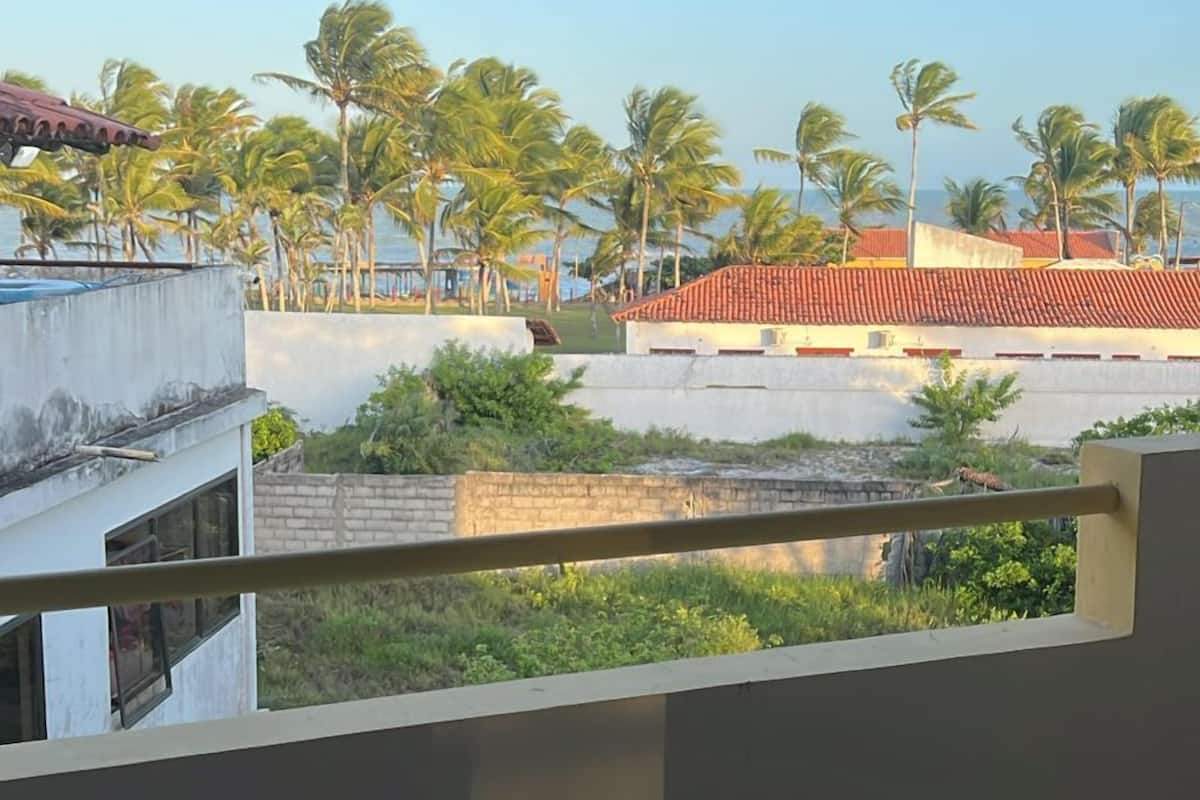 A balcony with a view of palm trees and buildings.