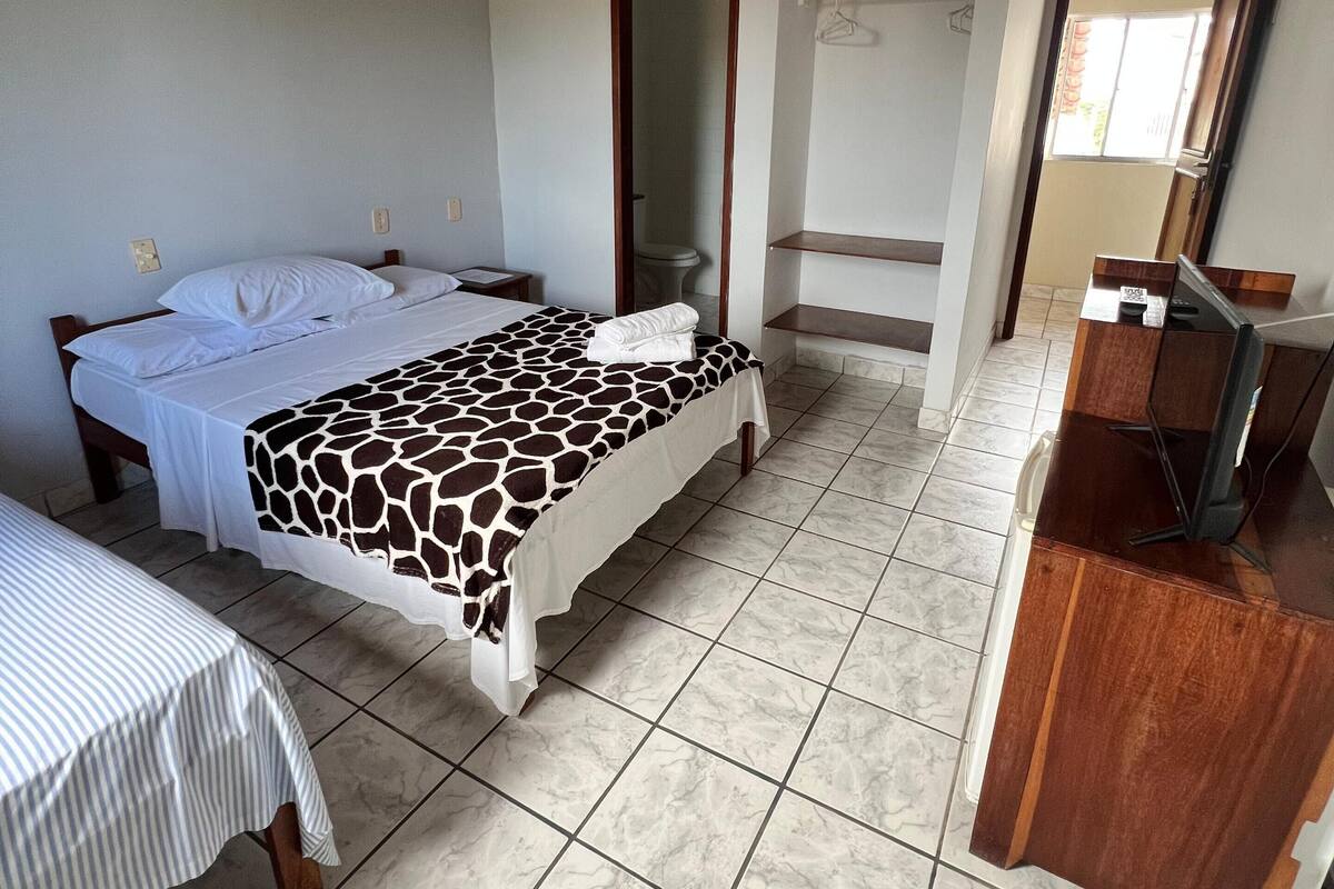 A bedroom with a bed, a desk, and a ceiling fan.