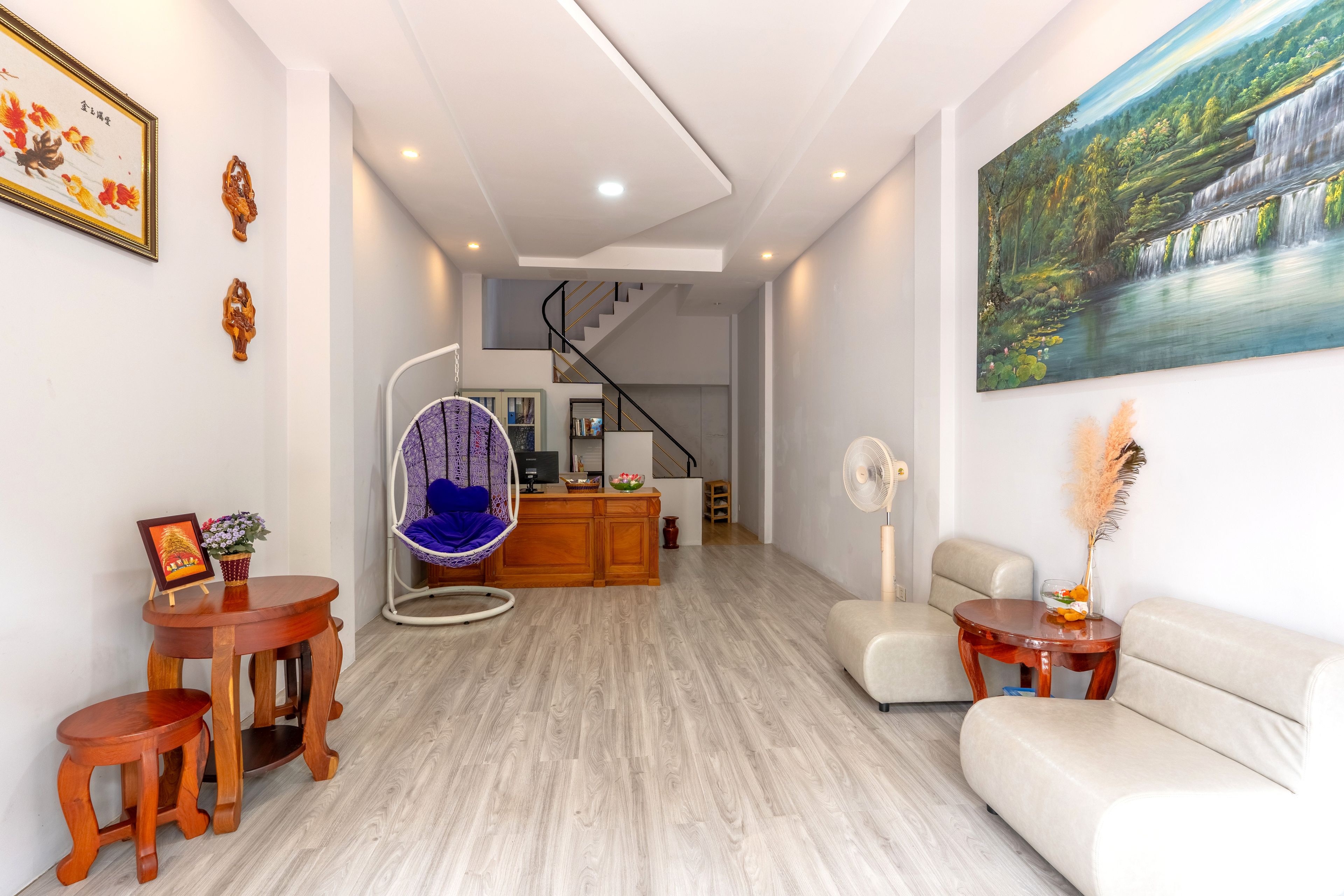 A modern living room with a hanging chair, a sofa, a dining area with a wooden table, and a staircase leading to another level.