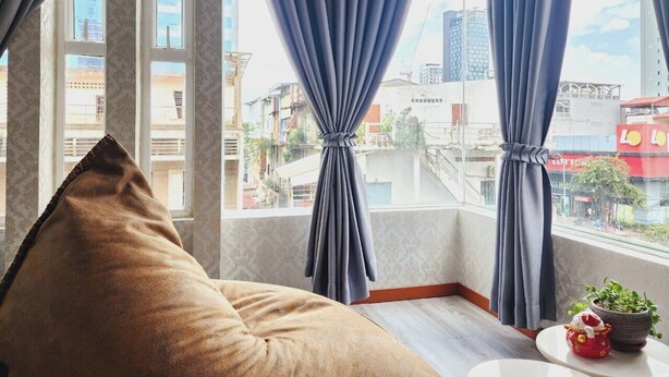 Una habitación con un ventanal grande, un sofá y una pequeña mesa con una planta.