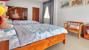 A bedroom with a large bed, a wooden bench, and a bookshelf.