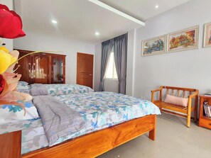A bedroom with a large bed, a wooden bench, and a bookshelf.