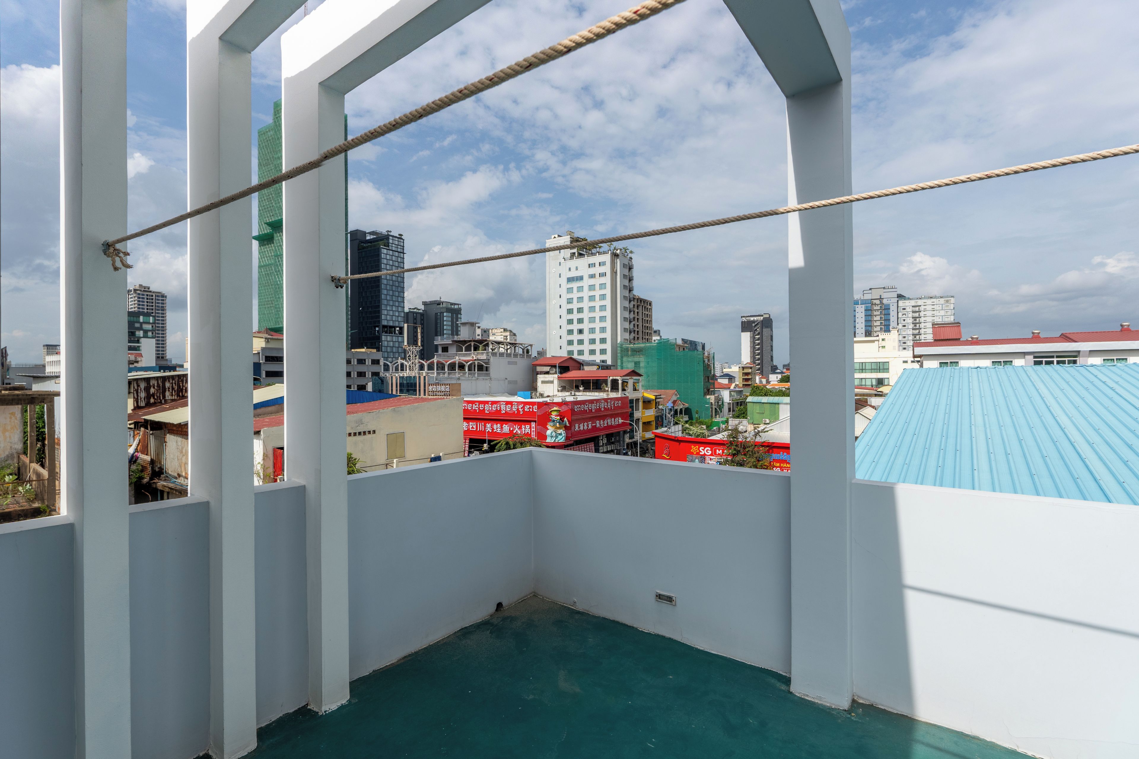 A balcony with a view of a cityscape, including buildings and a blue-roofed structure.