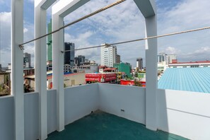 A balcony with a view of a cityscape, including buildings and a blue-roofed structure.