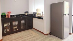 Una cocina moderna con encimera negra, refrigerador de acero inoxidable y piso de madera.