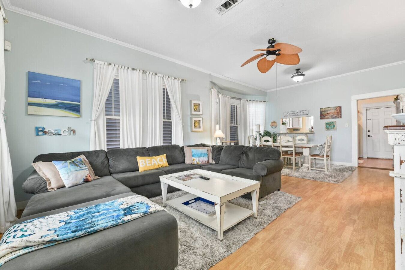 Un salon avec un canapé gris, une table basse et un ventilateur de plafond.