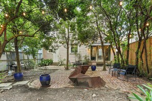 A patio area with brick flooring, metal benches, and potted plants. - New! Stately Home w Modern Flair Centrally Located (New Orleans)