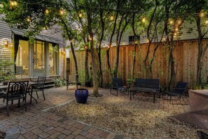 A patio with brick flooring, outdoor furniture, and string lights.