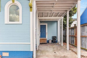 A covered porch with a blue door and steps leading to a house with light blue siding.