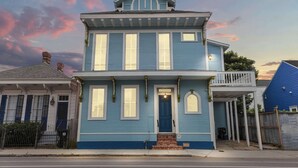 Une maison à deux étages avec un porche à l’avant, un garage et un petit balcon.