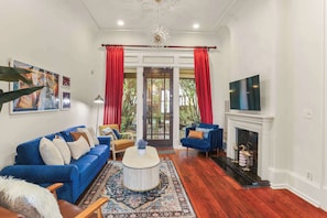 Una sala de estar con un sofá azul, una mesa de centro, una chimenea y un televisor.