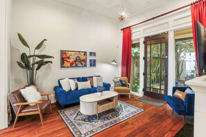 Un salon avec un canapé bleu, un fauteuil en cuir marron, une table basse et une grande plante.