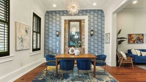 Un coin repas avec une table en bois, des chaises bleues et un tapis à motifs.