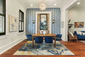 Un comedor con mesa de madera, sillas azules y alfombra estampada.